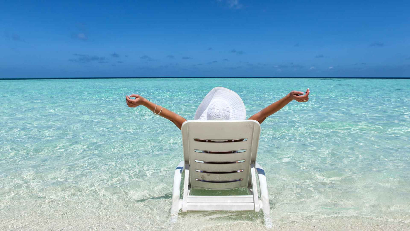 Frau im Liegestuhl von hinten vor einer Meereskulisse