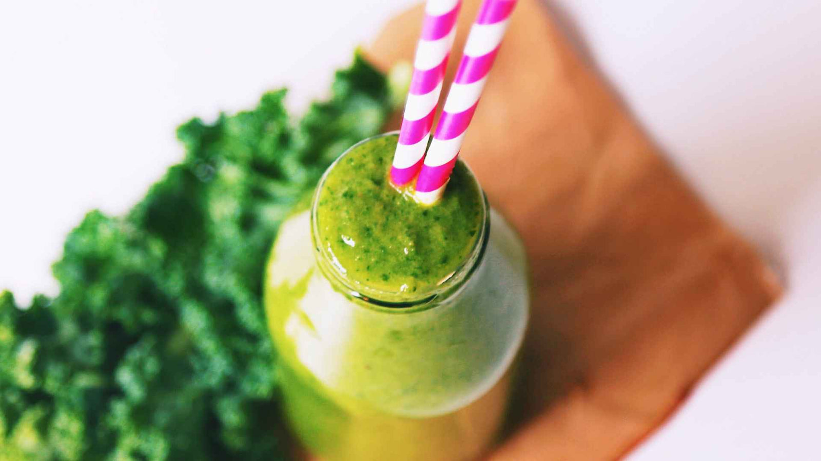 Grüner Smoothie im Glas mit Strohhalm drin