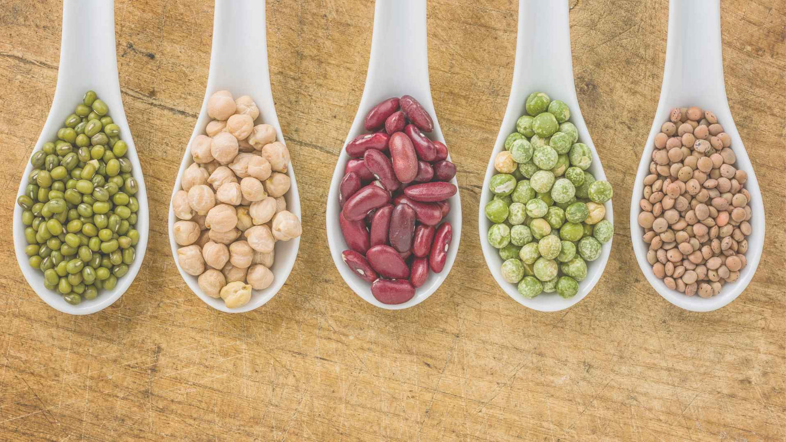 Hülsenfrüchte (Kirchererbsen, rote Bohnen, Erbsen) auf Löffeln präsentiert