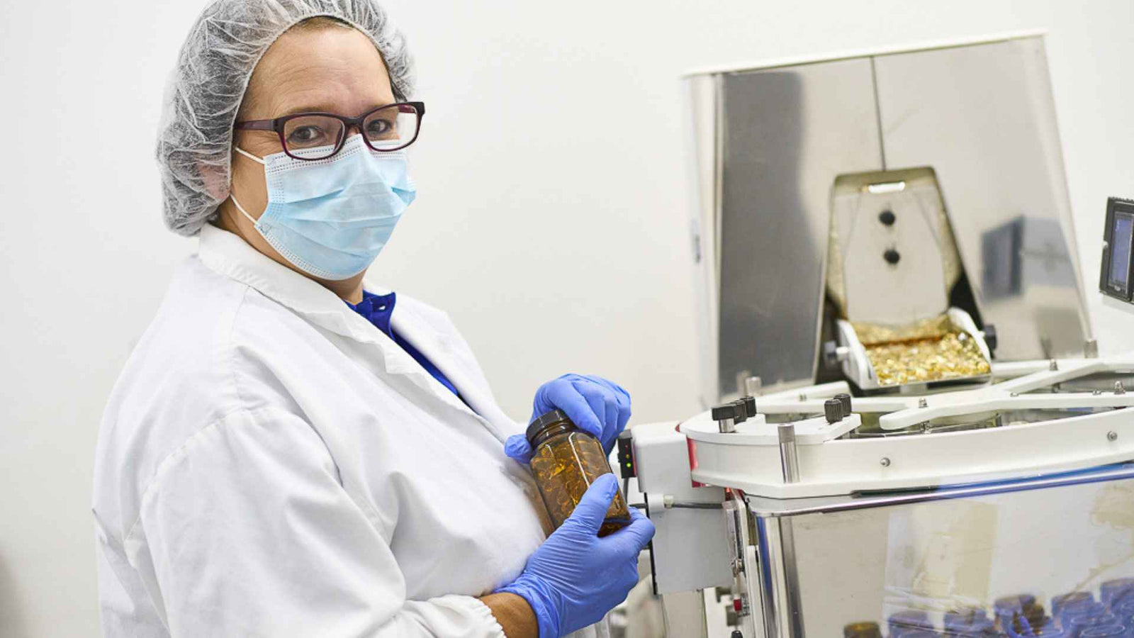 Mitarbeiterin mit Mundschutz, abgedeckten Haaren und weissem Schutzanzug in der Produktion von ArktisBio Pharma