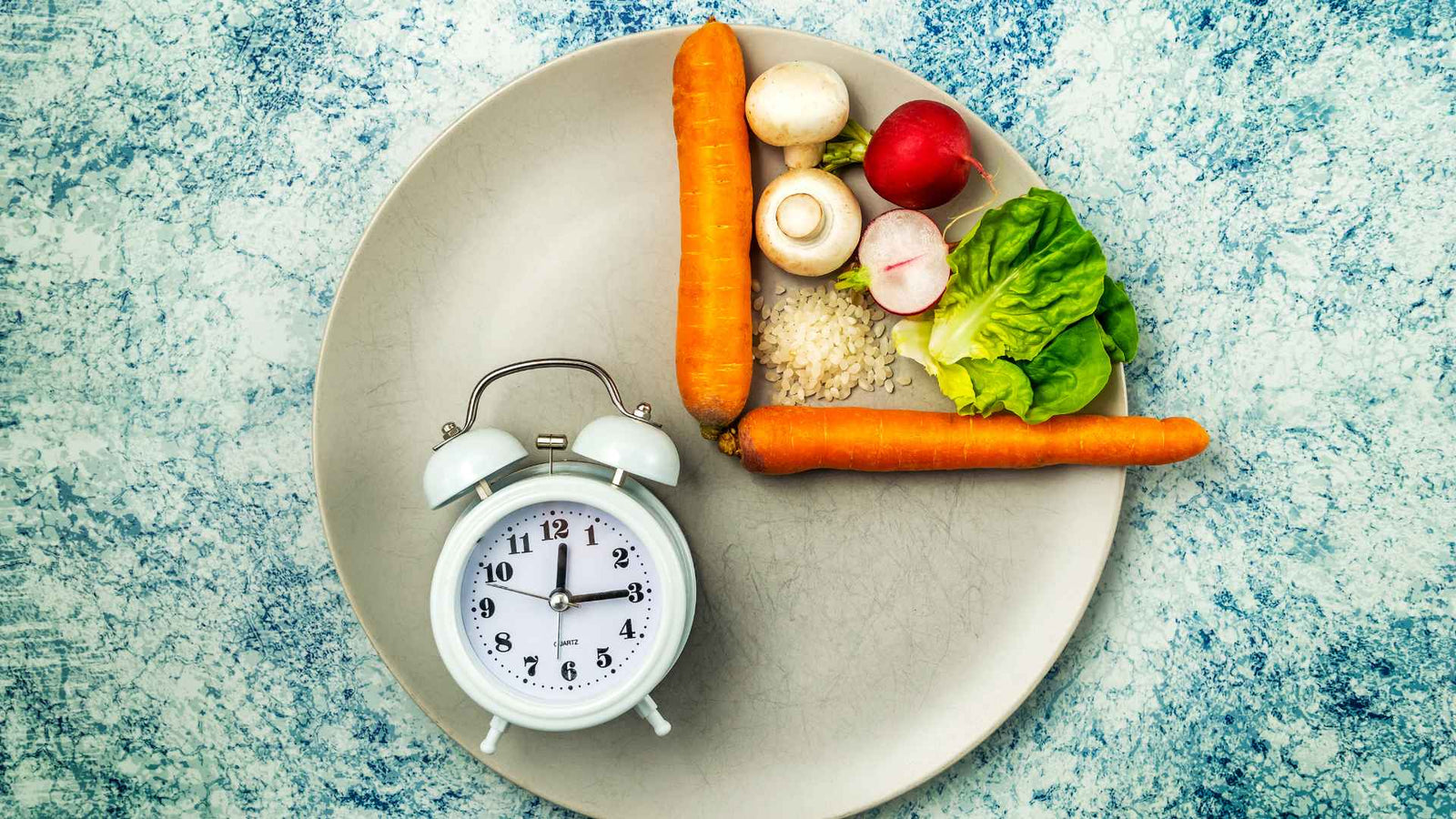 Teller mit Wecker und Gemüse um Intervallfasten darzustellen