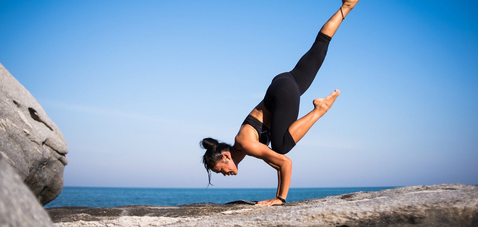 Frau praktiziert Yoga am Strand