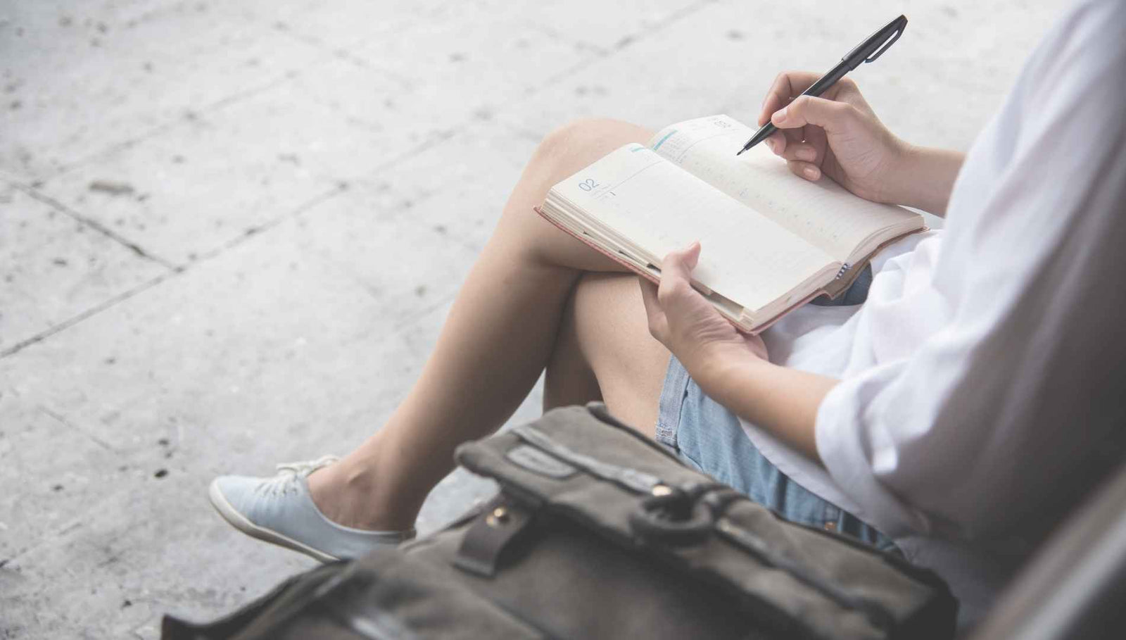 Frau sitzt auf der Bank und schreibt Tagebuch