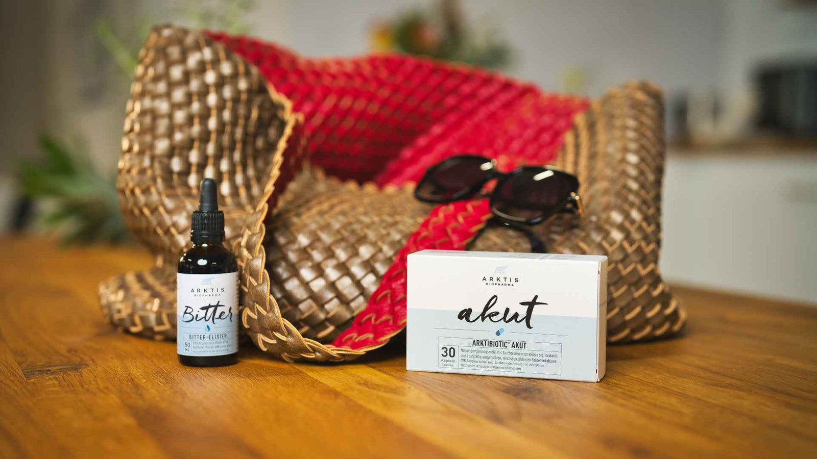 Reisetasche und Sonnenbrille, mit den Produkten Bitter und Akut im Vordergrund