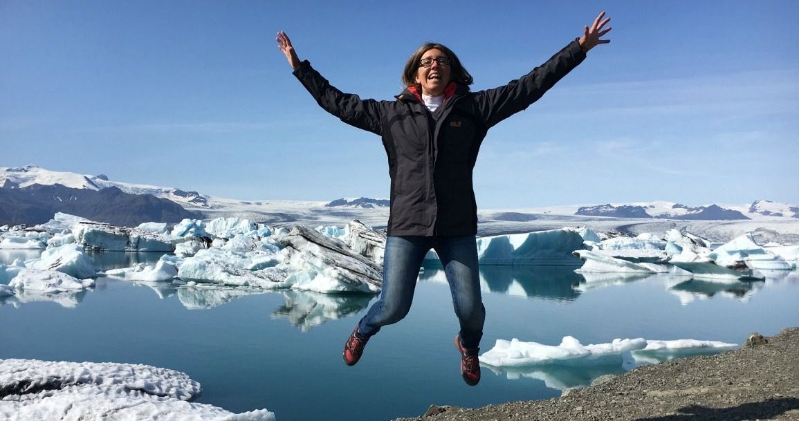 Ernährung und Unternehmertum ist der Frau wichtig, die vor einem Gletscher in die Luft springt.