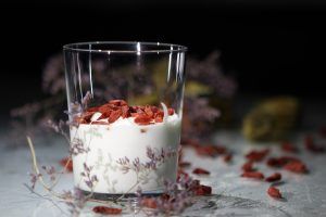 Joghurt und Gojibeeren sind schön aufbereitet in einem Glas mit Dekoration.