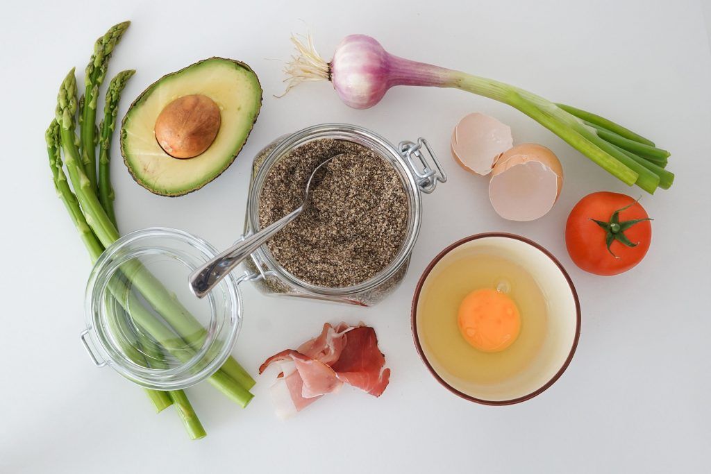 Mit Avocado, Spargel, Chia Samen in einem Einwegglas, Speck, Tomate, Frühlingszwiebel und einem Ei in einer Schale kann man gut kochen lernen.