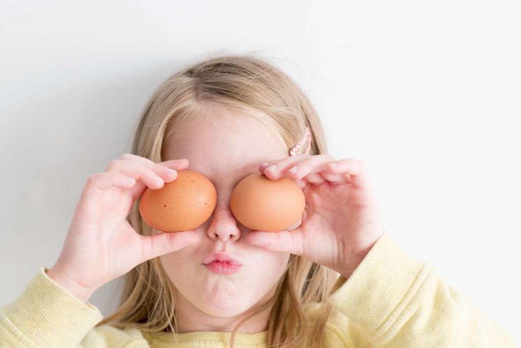 Mädchen hält sich zwei gesunde Eier vor die Augen.